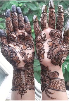 two hands with henna tattoos on them