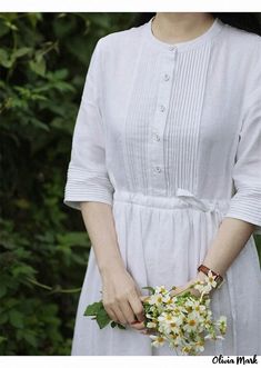 a woman wearing a white dress holding a bouquet of flowers