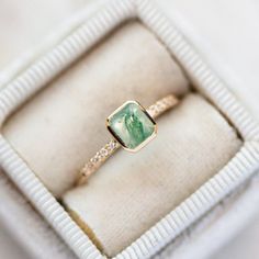 a close up of a ring in a box on a white surface with some diamonds