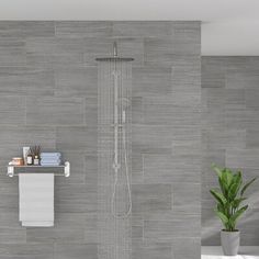 a bathroom with grey tiles and white fixtures, including a shower head in the center