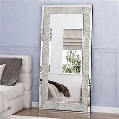 a large mirror sitting on top of a white bed in a room with blue walls