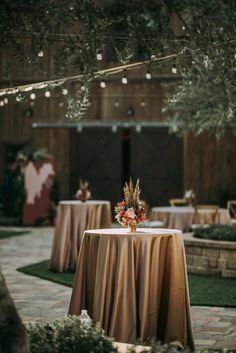 the table is set up for an outdoor event with lights strung from the ceiling and greenery