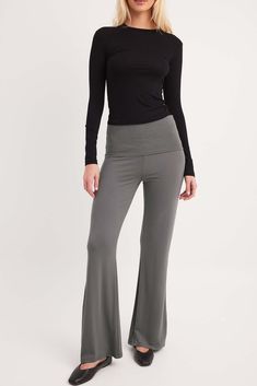 a woman in grey pants and black top posing for the camera with her hands on her hips