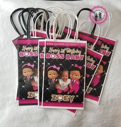 four birthday bags with the name boss baby in pink and black on them, sitting next to each other