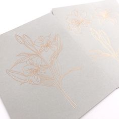 two cards with gold foil flowers on them, one is white and the other is light gray