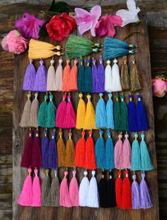 the tassels are laid out on a wooden board with flowers in the background