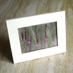 a white frame with pink flowers on it sitting on a counter top next to a wall