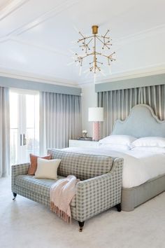 a bedroom with a bed, chair and chandelier