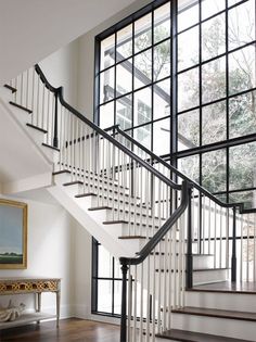 a white staircase with black railing and glass windows