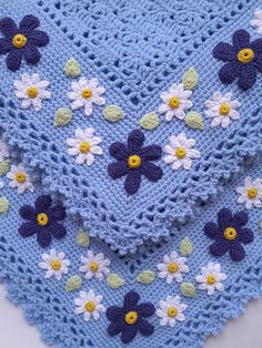 a blue crocheted blanket with flowers on it