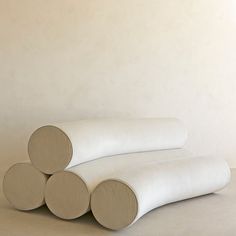 three round white cushions stacked on top of each other in front of a beige wall