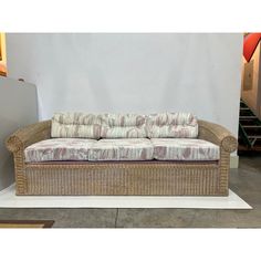 a wicker couch sitting on top of a white floor next to a stair case