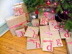 wrapped presents under a christmas tree with the word happy holidays spelled out on them in pink