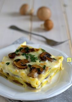 a white plate topped with lasagna covered in mushrooms