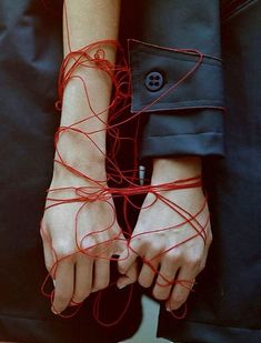 two hands with red string attached to them