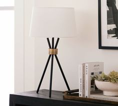 a lamp sitting on top of a wooden table next to a bowl and book shelf