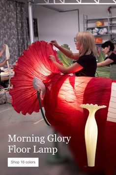 a woman is working on a large red object with the words morning glory floor lamp