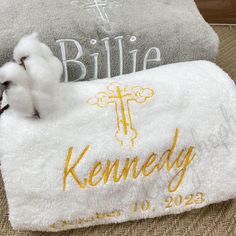 a small white dog laying on top of a towel next to a cross and name