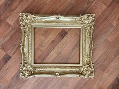 an empty gold frame sitting on top of a wooden floor