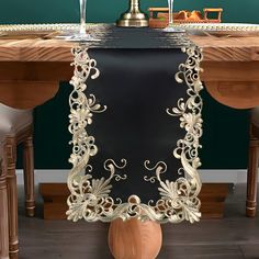 a table with a vase on top of it and an ornately decorated table runner