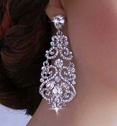 a close up of a woman's face wearing large earrings with crystal stones on them