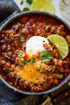 a bowl of chili with sour cream and cilantro garnish on top