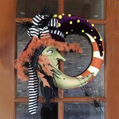 a halloween wreath with a witch's head and striped hat on it in front of a door