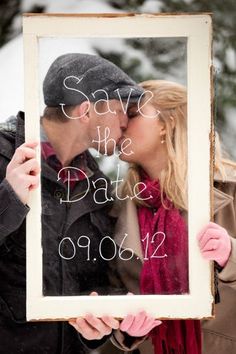 a man and woman kissing in front of a photo frame with the words save the date written on it