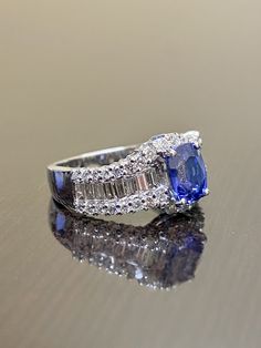 DeKara Designs Collection Metal- 18K White Gold, .750. Stones- Genuine Oval Ceylon Blue Sapphire 1.69 Carats. 38 Round Diamonds, 16 Baguette Diamonds H-I Color VS2-SI1 Color 1.09 Carats. Beautiful Art Deco Inspired Entirely Handmade Oval Shaped Ceylon Blue Sapphire Diamond Baguette Engagement Ring Created in 18K White Gold. There is a beautiful oval blue sapphire in the center of the ring that is professionally set between four prongs. The top of and the bottom of the sapphire has round prong se Blue Diamond Ring With Baguette Diamonds, Luxury Oval Tanzanite Diamond Ring, Oval Tanzanite Diamond Wedding Ring, Luxury Baguette Cut Sapphire Ring, Oval Diamond Ring With Baguette Diamonds, Oval Blue Sapphire Ring With Diamond Accents, Exquisite Oval Blue Sapphire Ring, Luxury Sapphire Oval Rings, Oval Tanzanite Wedding Ring