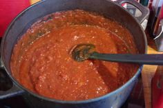 a pot filled with red sauce on top of a stove