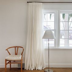 a chair sitting in front of a window next to a lamp on top of a hard wood floor