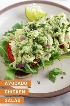 an avocado chicken salad with lettuce and tomatoes on a white plate