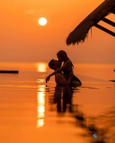 two people in the water at sunset with one holding the other's head and kissing