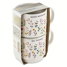 two coffee mugs with floral designs on them in a cardboard box, one is white and the other is pink