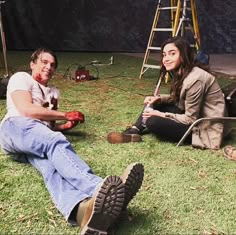 two people sitting in the grass with paint on their faces and one holding an apple