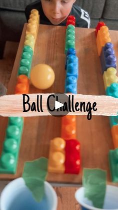 a young boy is sitting at a table and playing with some sort of game called ball challenge