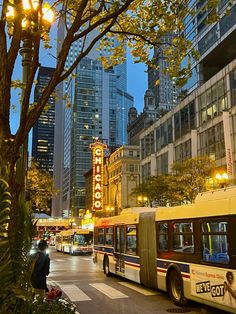 a city street filled with lots of traffic next to tall buildings and trees in the evening