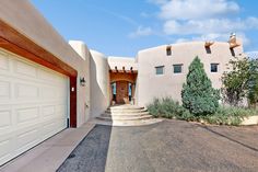 an adobe style home with two garages and steps leading up to the front door