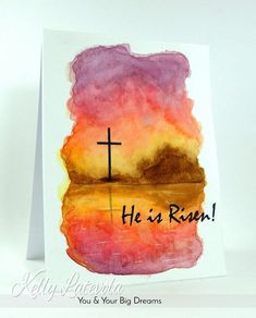 a card with a watercolor painting of a cross and the words he is risen