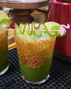 two glasses filled with green liquid and topped with cucumber garnishments