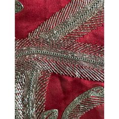 an embroidered red and silver fabric with metallic leaves on the side, in front of a dark red background