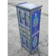 an artisticly painted cabinet sits on the pavement