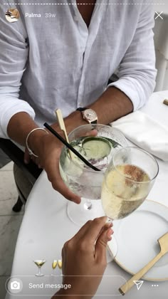 two people holding wine glasses at a table with plates and utensils on it