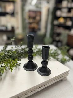 two black candlesticks sitting on top of a table