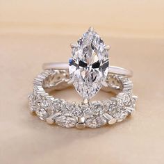 a pear shaped diamond engagement ring set on top of a beige surface with diamonds around the band