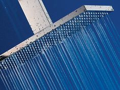 a shower head with water running down it's side and blue sky in the background