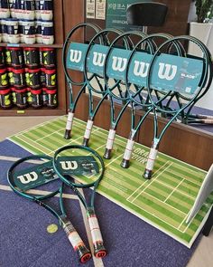 four tennis rackets are sitting on the floor in front of a store display case