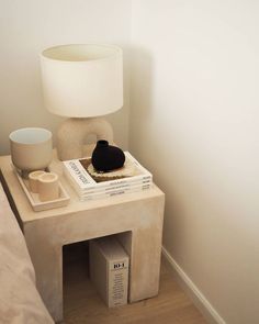 a small table with a lamp on top of it next to a book and cup