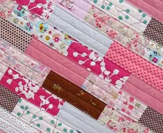 a close up of a patchwork quilt with pink and white flowers on the border