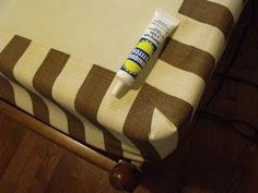 a tube of toothpaste sitting on top of a striped bed sheet with a wooden foot board